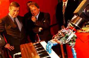 Landespräsident Clement schaut erstaunt einem Robotvirtuosen  im Heinz Nixdorf Computermuseum zu.